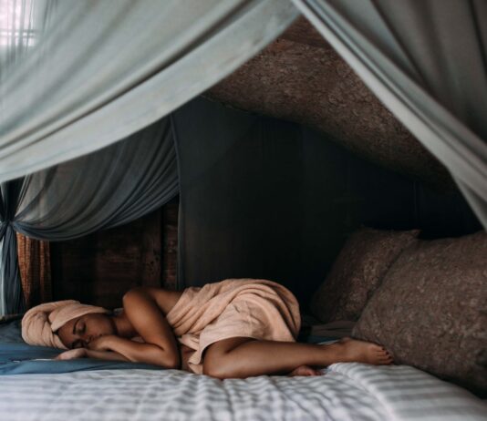 The Role of Sleep in Weight Management woman lying on bed wrapped around a towel