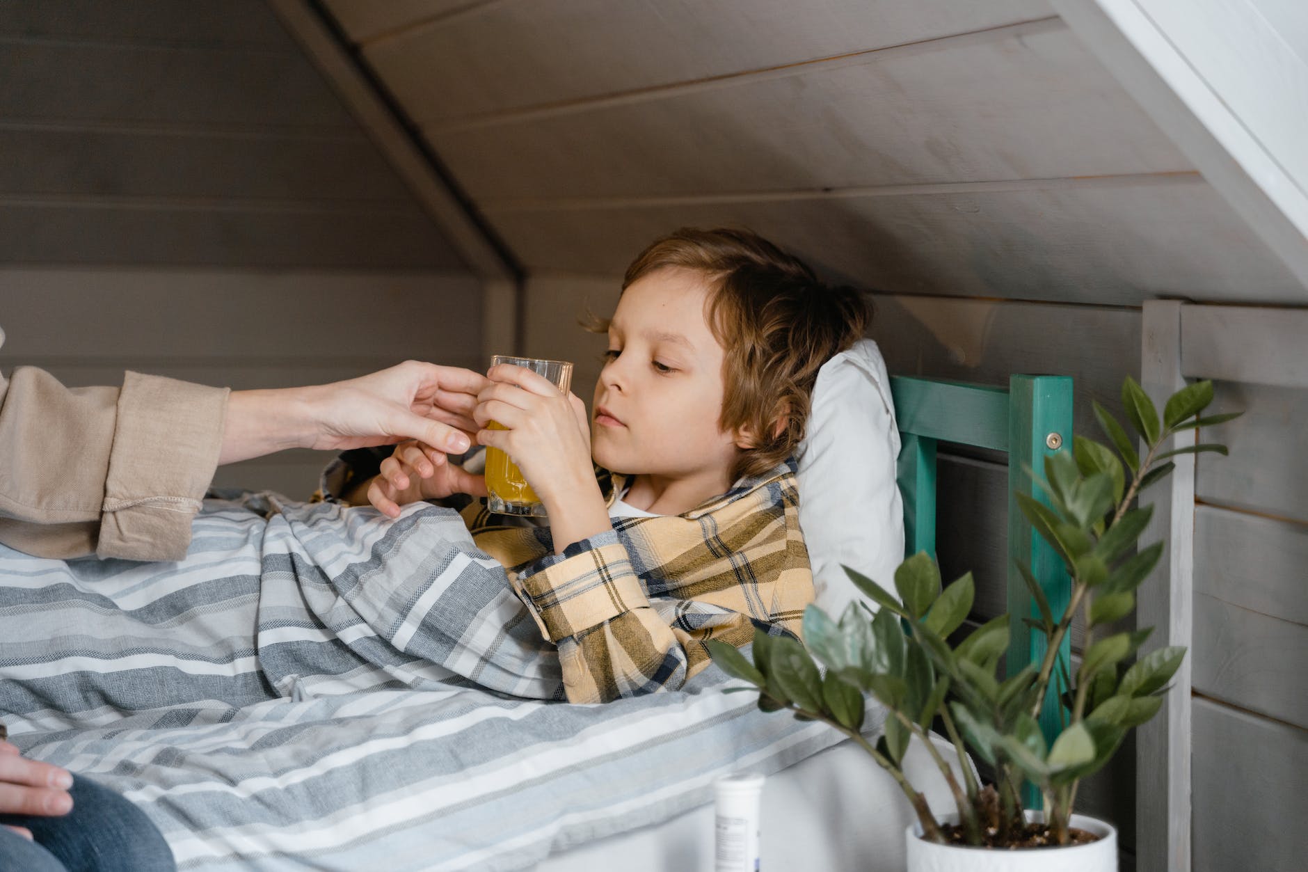 boy holding a glass while lying on the bed