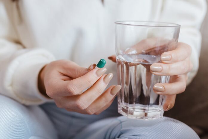 woman holding pill and glass of water