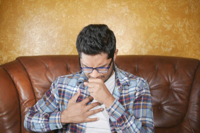 a man in a plaid shirt coughing