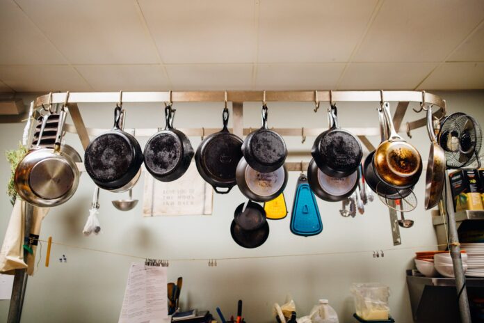 assorted frying pans hanging on pot rack