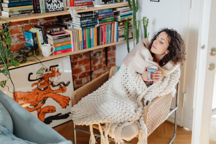 woman feeling cold wrapped in a shawl and drinking tea