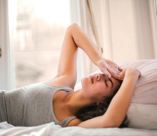 Struggling with Your Sleep? Experts Share 6 Tips That’ll Help woman in gray tank top lying on bed